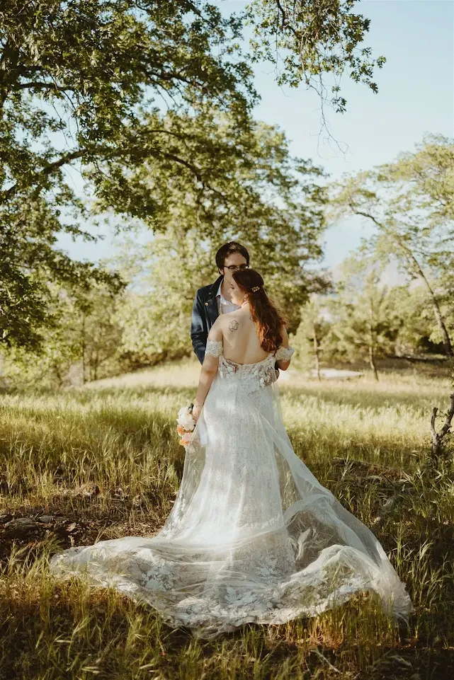Сouple wearing a white gown and a black suit in the woods