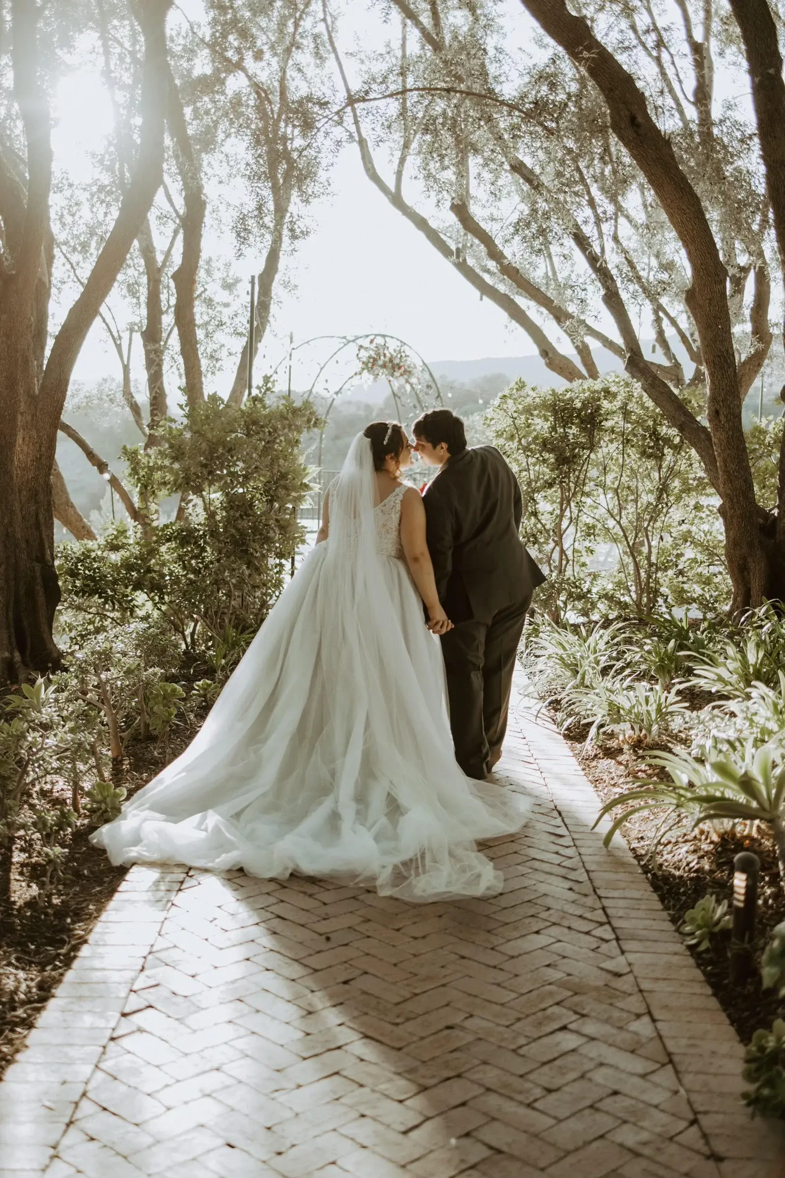 Сouple wearing a white gown and a black suit under the tree